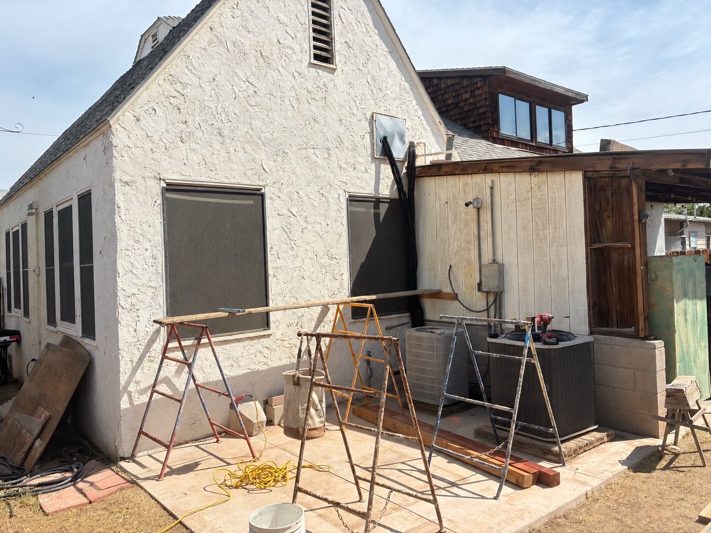 Before: an open concrete area at the rear corner of the house